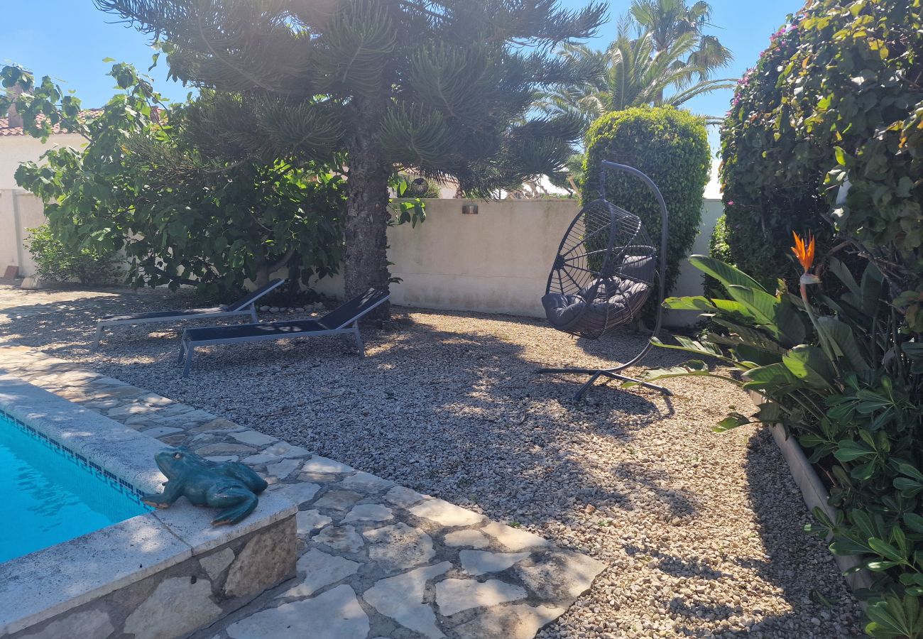 Zona de tumbonas en el jardín con un fantástico sillón colgante bajo la sombra de un gran árbol.