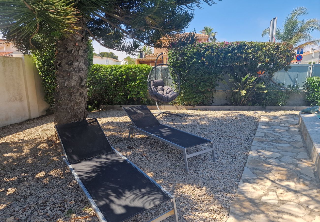 Vistas desde la terraza hacia la zona de tumbonas con el sillón colgante bajo la sombra del gran árbol.