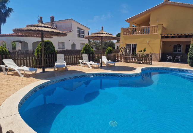 Vistas de la piscina gigante con sombrillas de paja fijas hacia la casa vacacional Eva.
