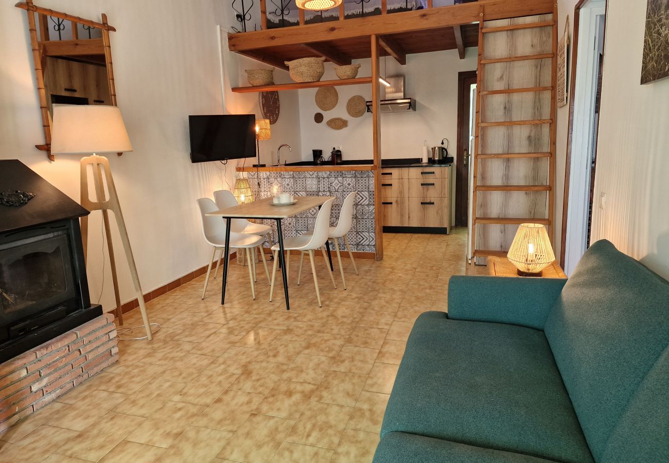 Salón-comedor abierto con chimenea y un altillo superior con un segundo sofá.