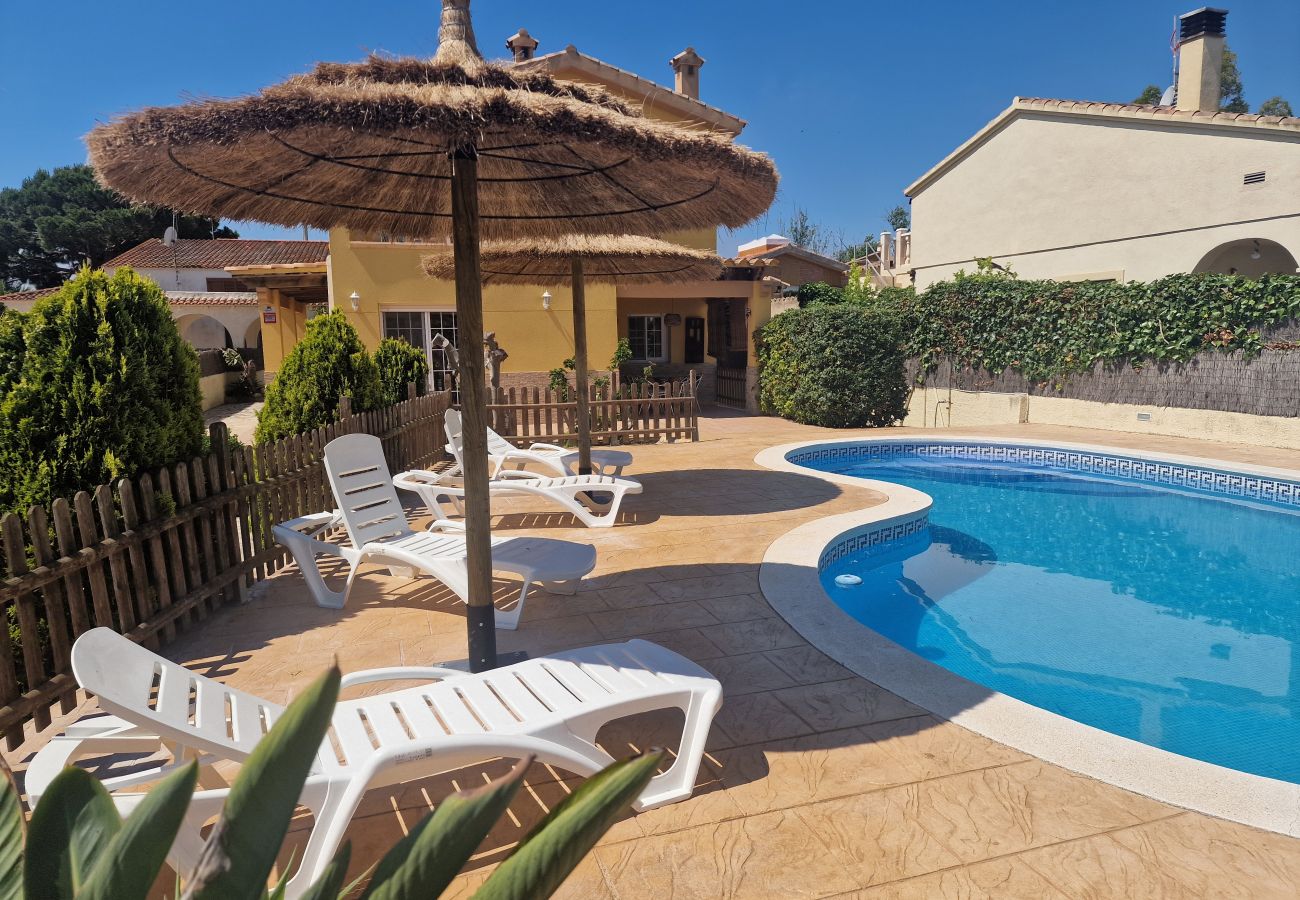 Großzügige Liegefläche mit Strohsonnenschirmen am Pool mit Blick auf das Ferienhaus Eva.